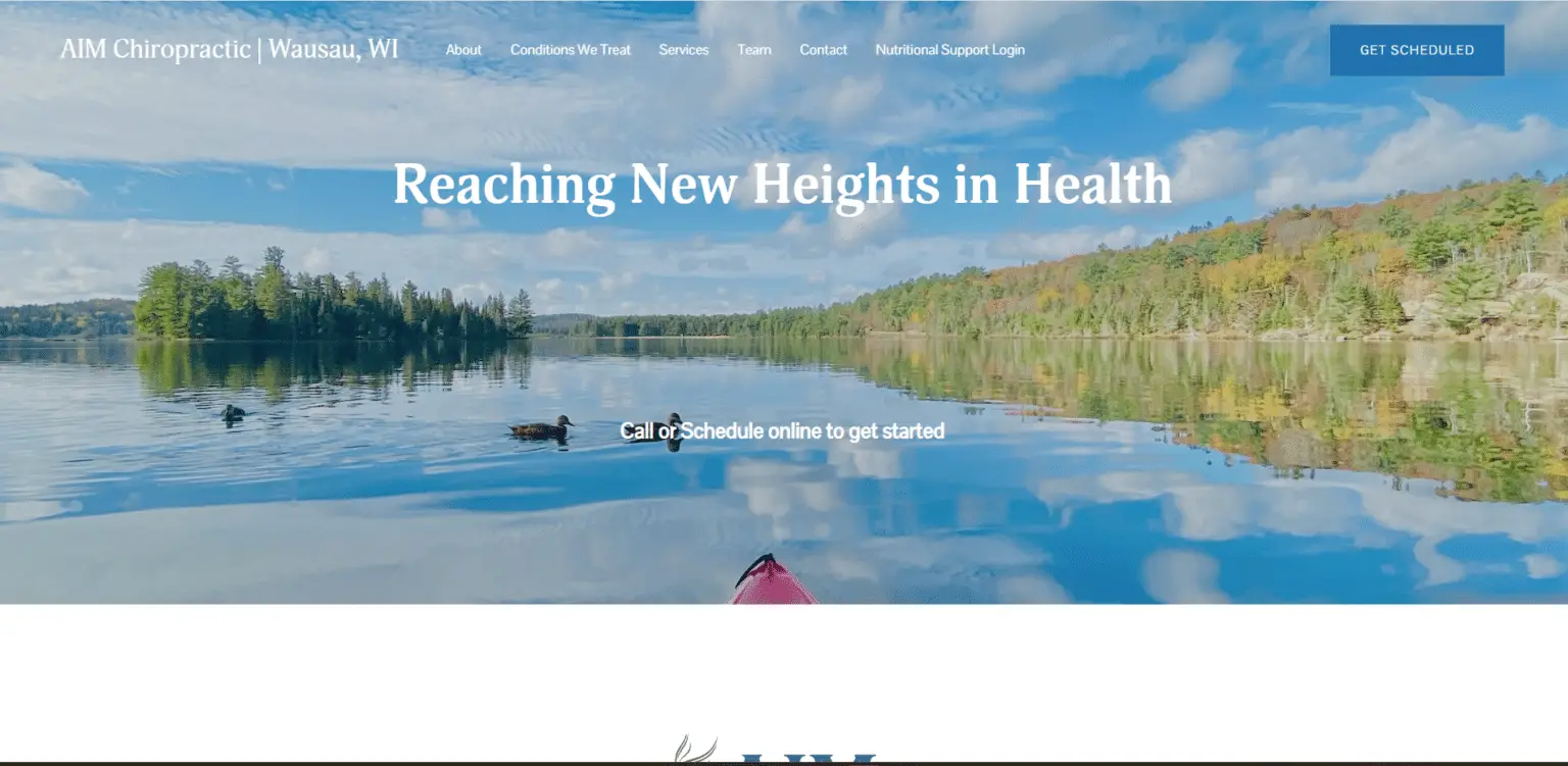 AIM Chiropractic website homepage featuring serene lake view with trees, emphasizing health and wellness theme, showcasing "Reaching New Heights in Health" tagline.